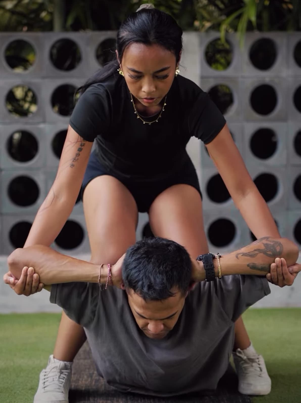 Ain, a Bali-based stretch therapist, guiding a client through an assisted stretch outdoors.